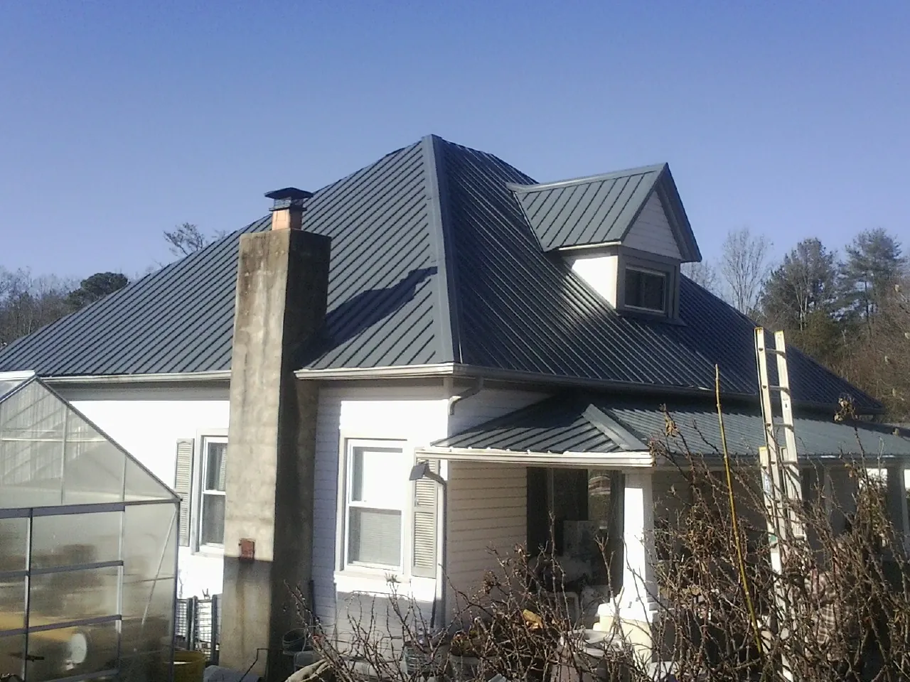 Dark blue standing seam metal roof on a white farmhouse with dormer — Slate & Tile Roof Repair by Roofing Brothers in Las Vegas