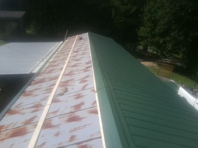 Old rusted panels beside newly installed green metal roofing — Wind Damage Roof Repair by Roofing Brothers in Las Vegas