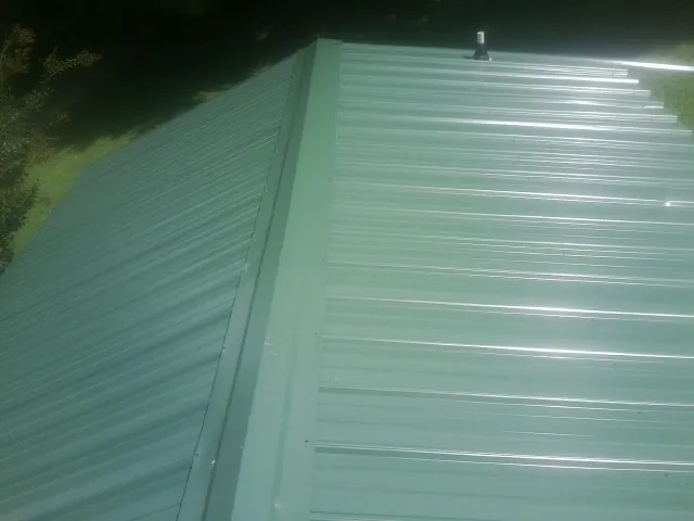 New green metal panels meeting at the ridge of a roof — Flat Roof Repair work by our crew in Las Vegas