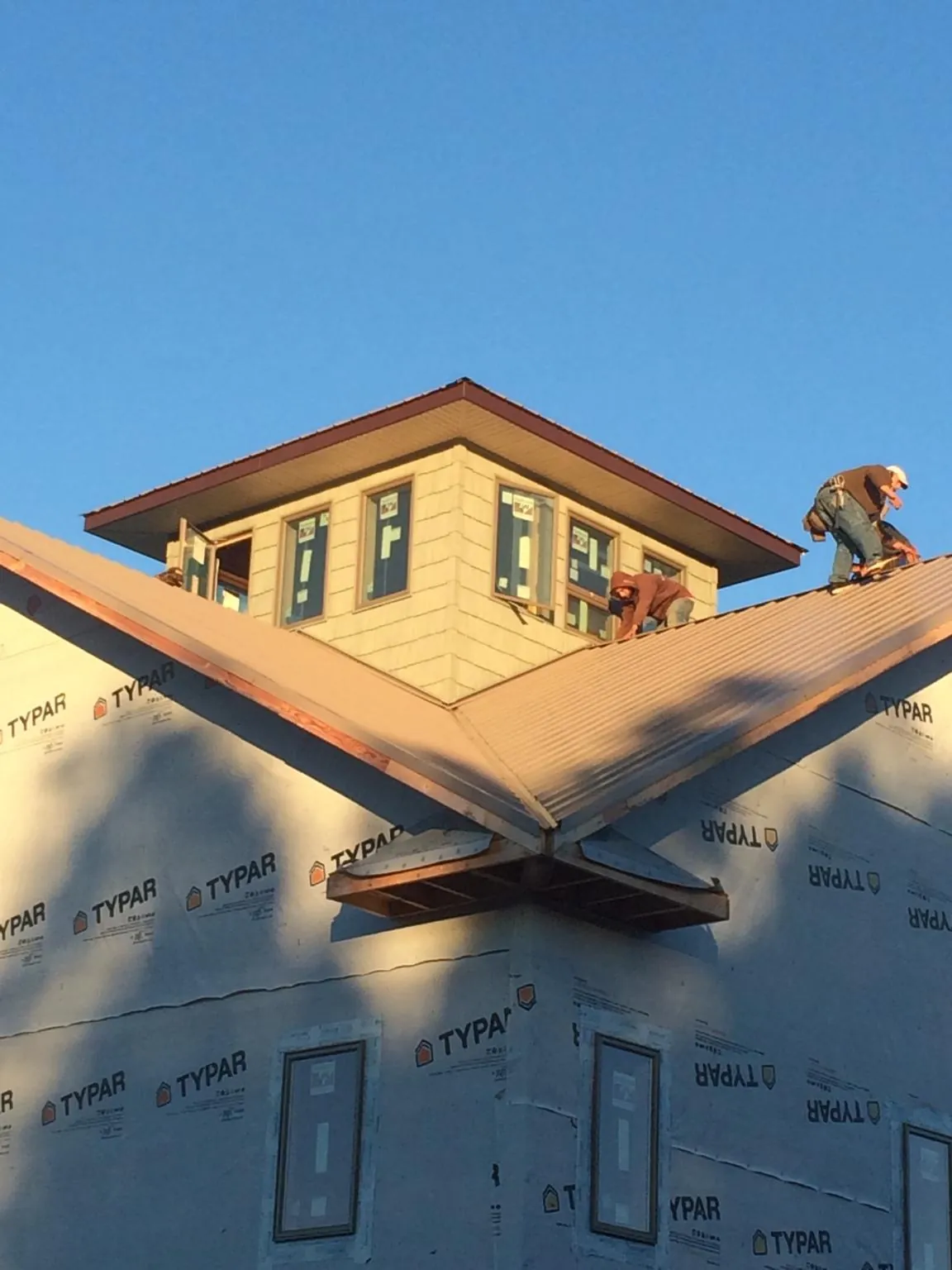 Roofers working around a rooftop cupola on a new metal roof at sunset — Roof Waterproofing in Las Vegas by Roofing Brothers